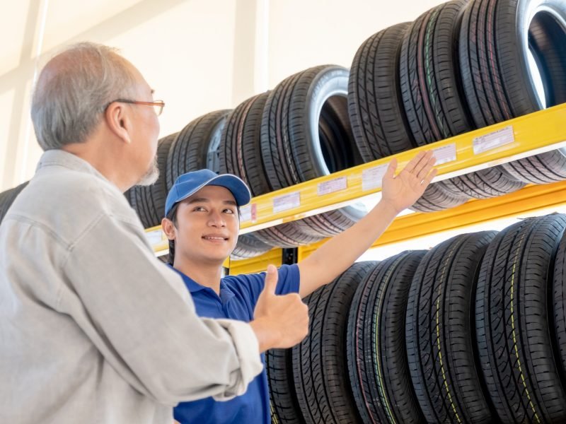 Asian worker of auto parts shop explain and suggest good quality tire to senior customer man and he look happy. Concept of good practice and environment in office support business system.